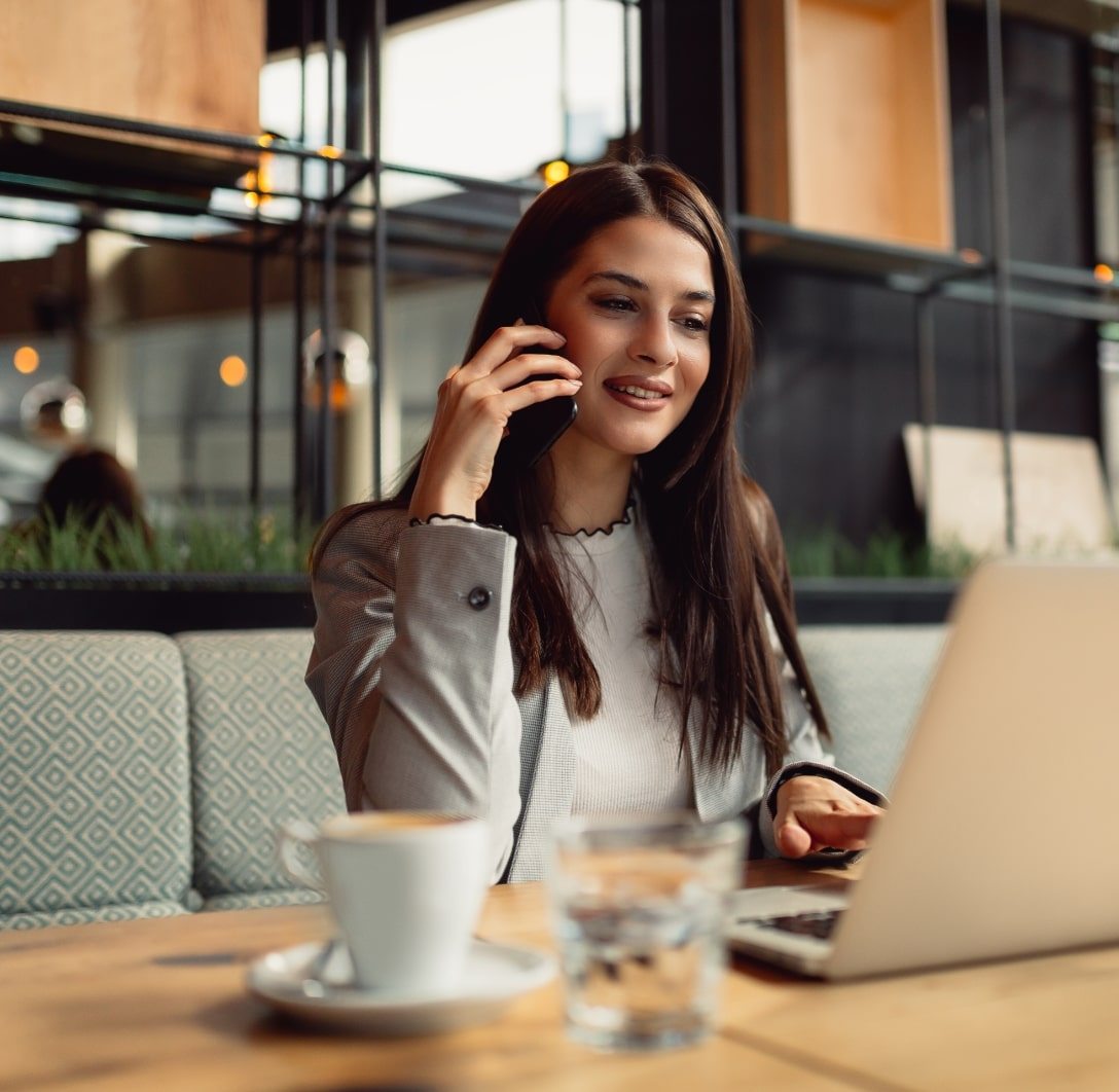 Woman in office on phone call while using laptop, symbolizing expert website design, SEO services, and social media marketing consultation
