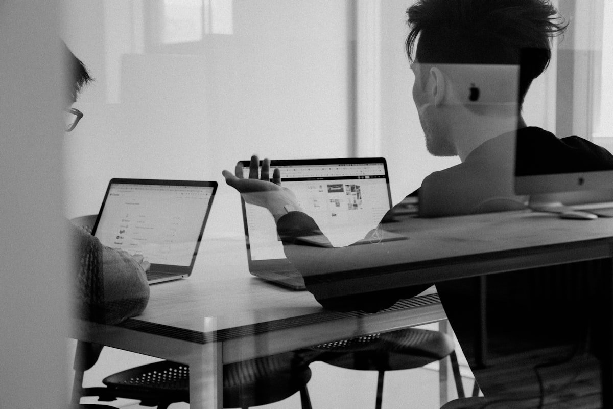 Person reviewing a website on a desktop computer beside a laptop
